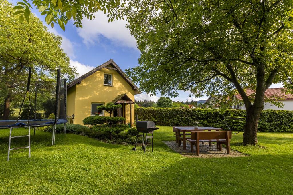 a yellow house with a picnic table in the grass at Domek pod Orzechem in Kudowa-Zdrój
