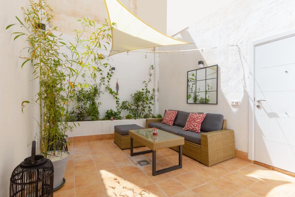 een woonkamer met een bank en planten bij Precioso apartamento con patio y dos habitaciones en el barrio de Picasso in Málaga