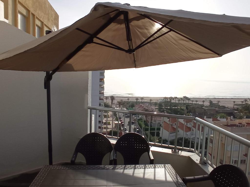 a table and chairs with an umbrella on a balcony at Bahamas II Solo Familias Serviplaya in Playa de Gandia