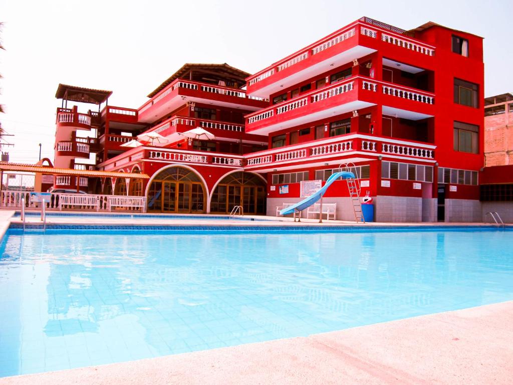 a large swimming pool in front of a red building at Hotel Los Arcos de Imperial in San Vicente de Cañete