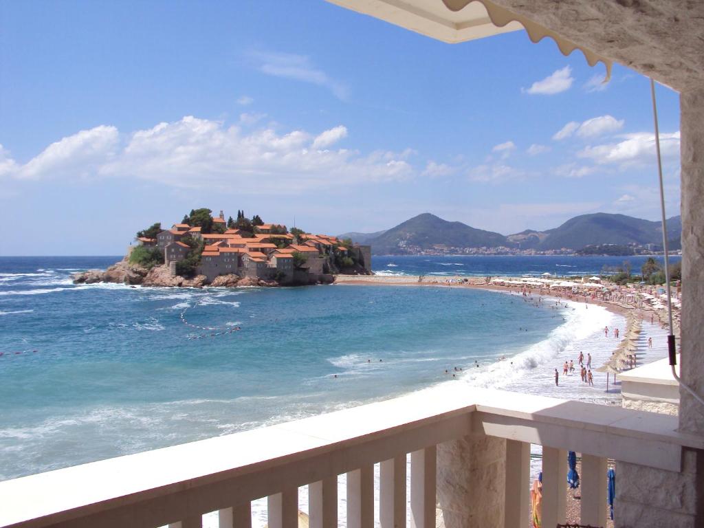 a view from a balcony of a beach with a resort at Beachfront First Line View in Sveti Stefan