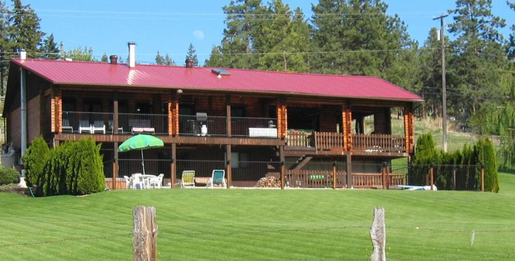 duży drewniany dom z czerwonym dachem w obiekcie Kamloops Log Home Bed and Breakfast w mieście Kamloops