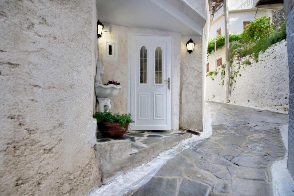 a white door in a white building with a stone walkway at Παραδοσιακό σπίτι στο χωριο in Áyioi Dhéka