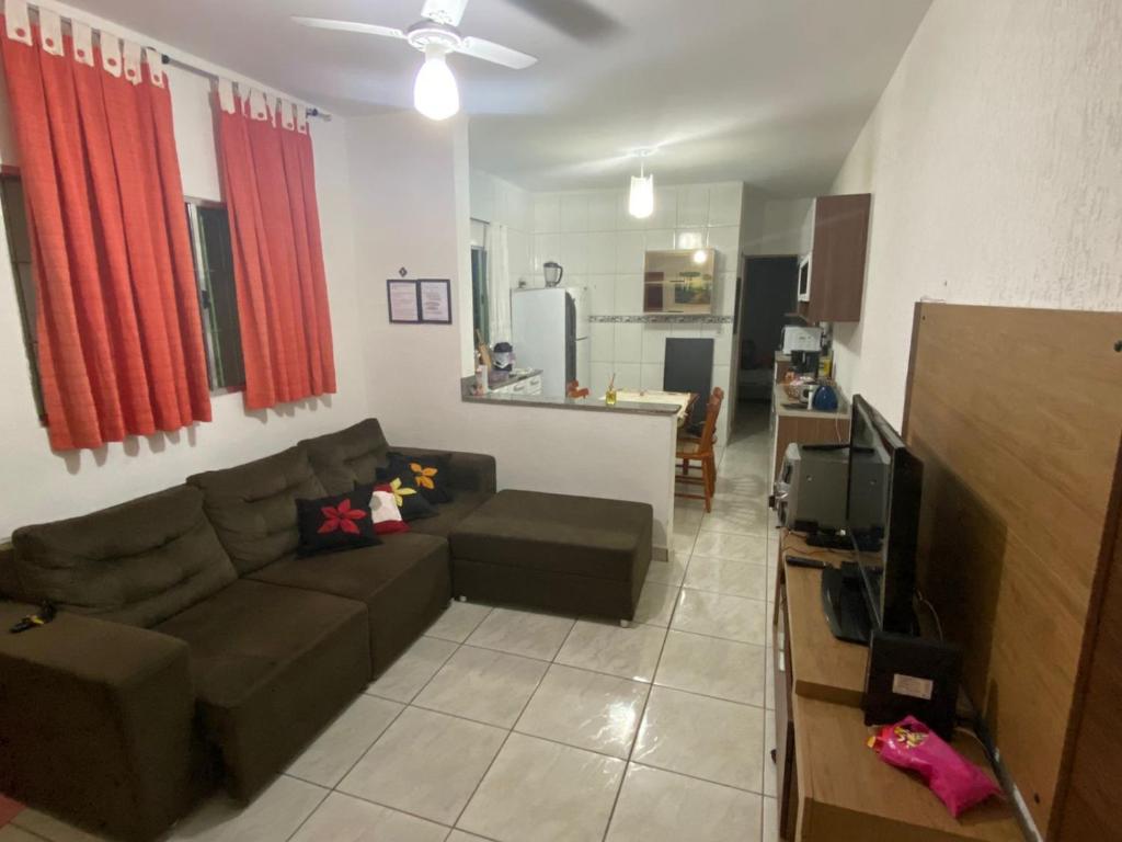 een woonkamer met een bank en een keuken bij Lar Doce mar in Mongaguá