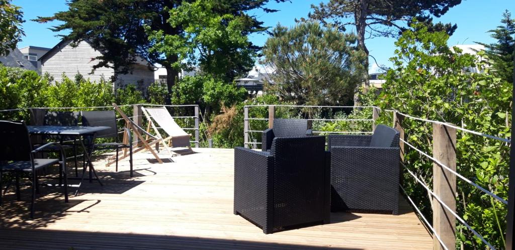 una terrazza in legno con sedie e tavolo di Villa Jules Petit Gîte a Agon Coutainville