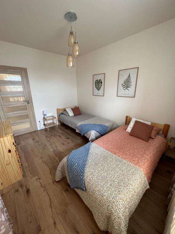 two beds in a room with wooden floors at Apartament Poznańska in Suwałki