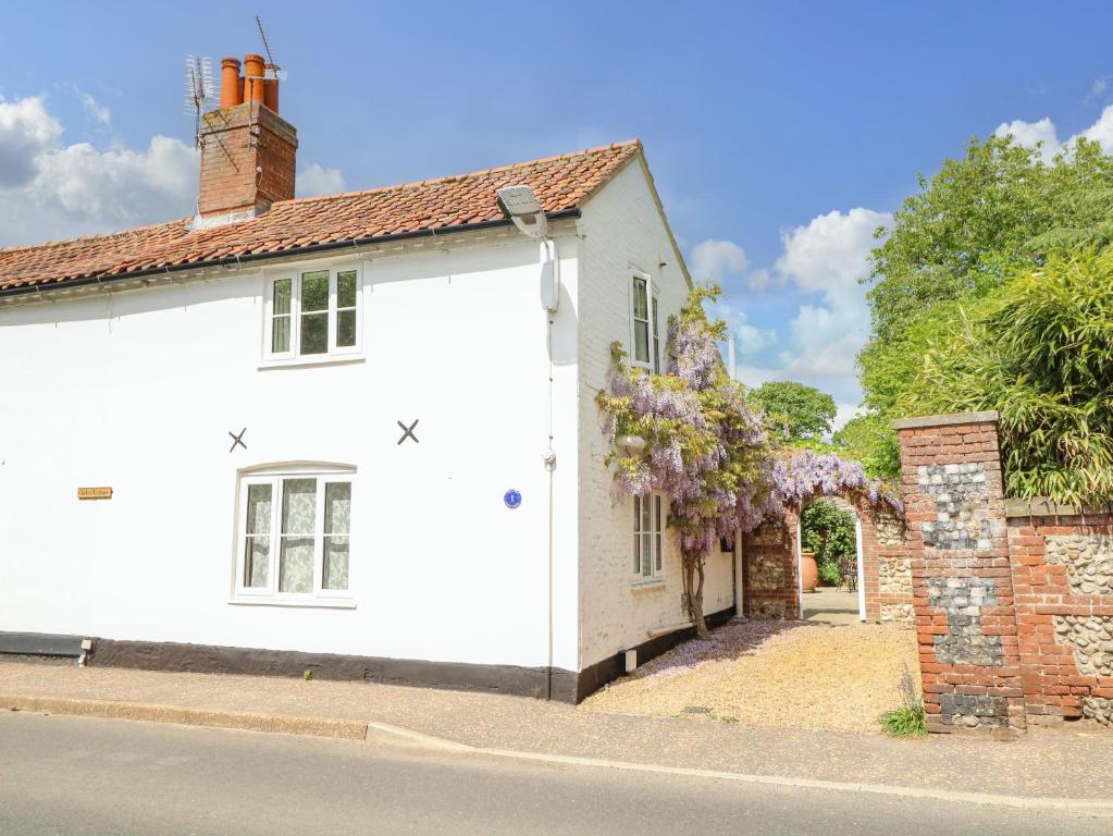 een wit huis met een stenen muur en een boog bij 1 Chelsea Cottage in North Elmham