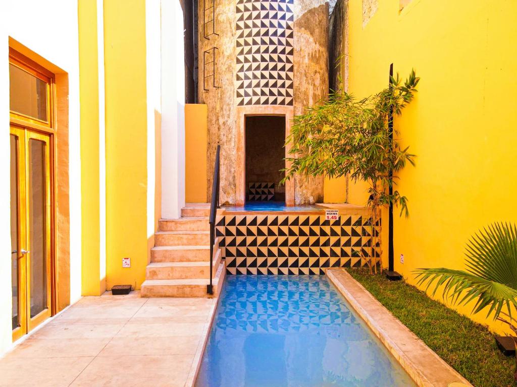 una casa con piscina junto a un edificio amarillo en Hotel La Nacional By Kavia, en Mérida