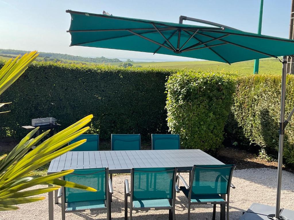 uma mesa com cadeiras e um guarda-sol verde em Sur les routes de la mer em Saint-Inglevert