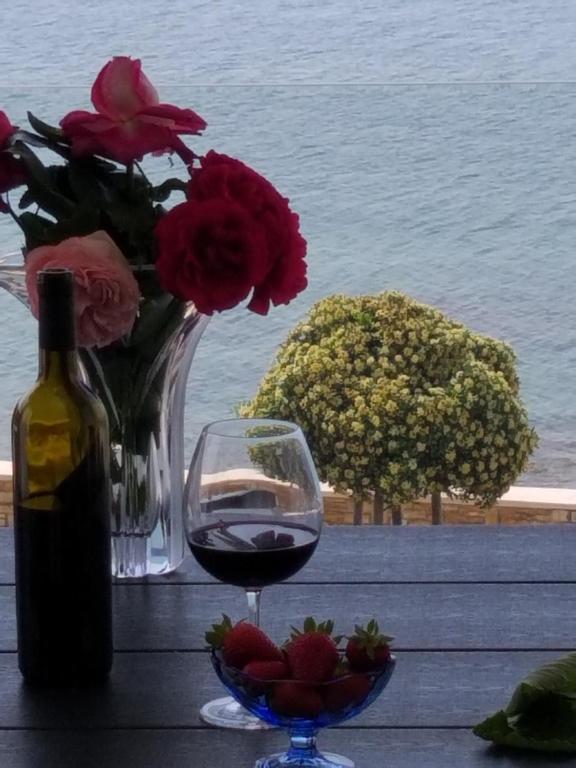 a glass of wine next to a vase of flowers at Sanja Apartments Rivarela in Novigrad Istria