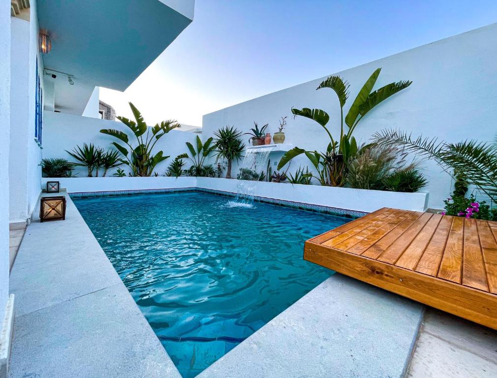 a swimming pool with a wooden table and a swimming pool at Dar Colibri - Maison d'hôtes à Kélibia in Kelibia