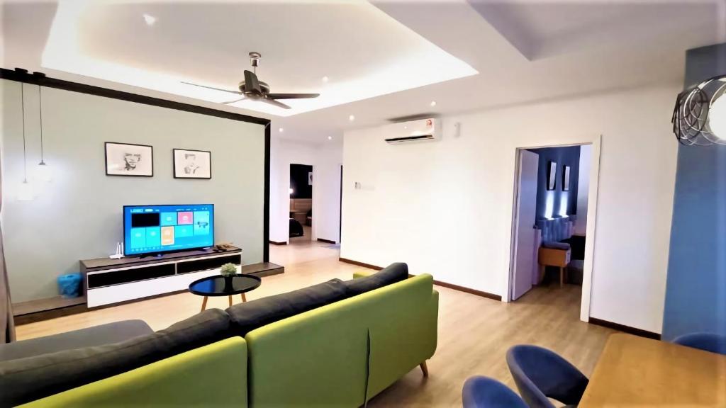 - un salon avec un canapé vert et une télévision dans l'établissement Limbongan Executive Suites Melaka By GGM, à Malacca