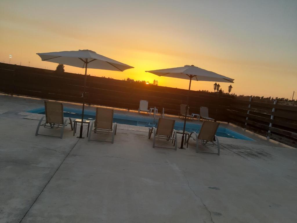 a group of chairs and umbrellas next to a pool at Sunset Villa in Nea Paphos