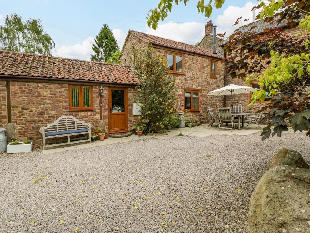 a stone cottage with a bench and an umbrella at Sutton Barn in Ross on Wye