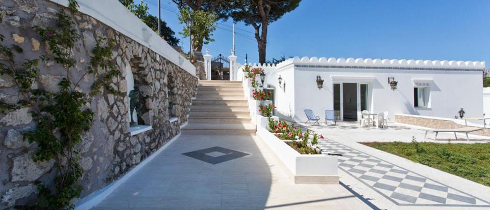 a walkway leading to a white building with a stone wall at Villa Raffaella in Capri