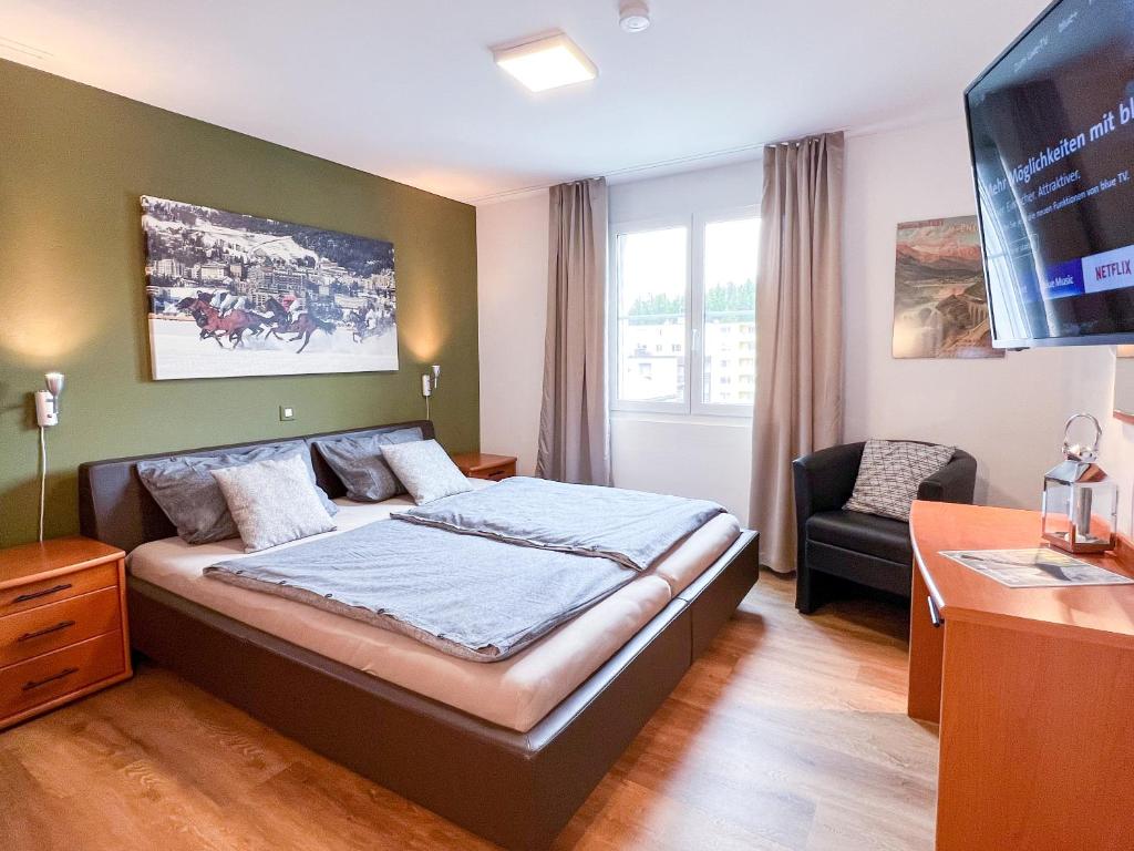 um quarto de hotel com uma cama e uma televisão em swissme - 100qm - Balkon - 2 Bäder - Parkplatz - Fußbodenheizung em St. Moritz