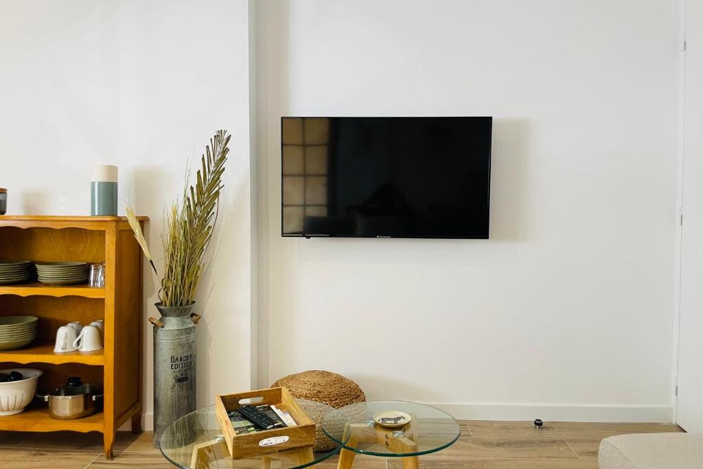 - un salon avec une table en verre et une télévision murale dans l'établissement Le Chenonceau  Charme et douceur Tourangelle, à Tours
