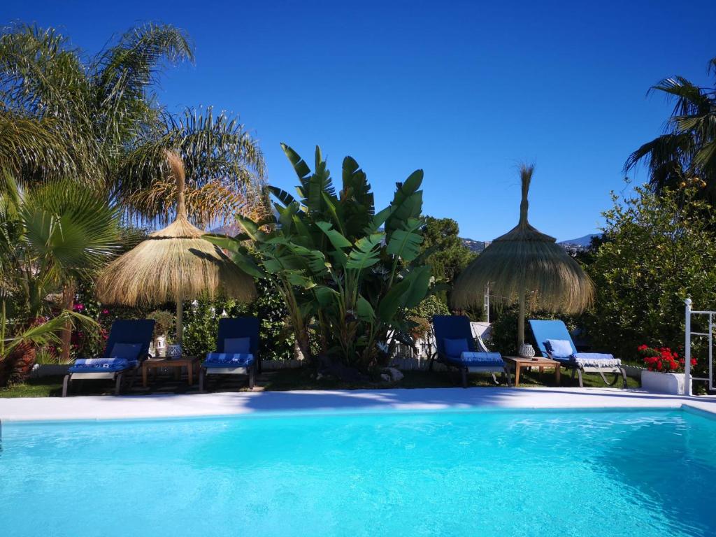 a swimming pool with chairs and umbrellas at Casa Silca in Marbella