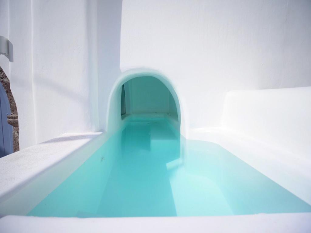 a swimming pool in a white room with blue lighting at Oinos Luxury Suites in Foinikiá