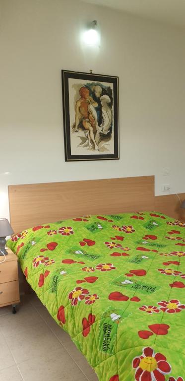 un letto con una coperta verde con dei fiori sopra di Le Acacie rooms - ex B&B a Termoli