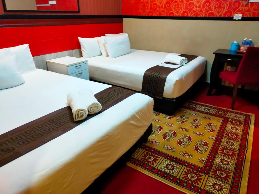 a hotel room with two beds and a red wall at HOTEL SRI IMPIAN in Johor Bahru