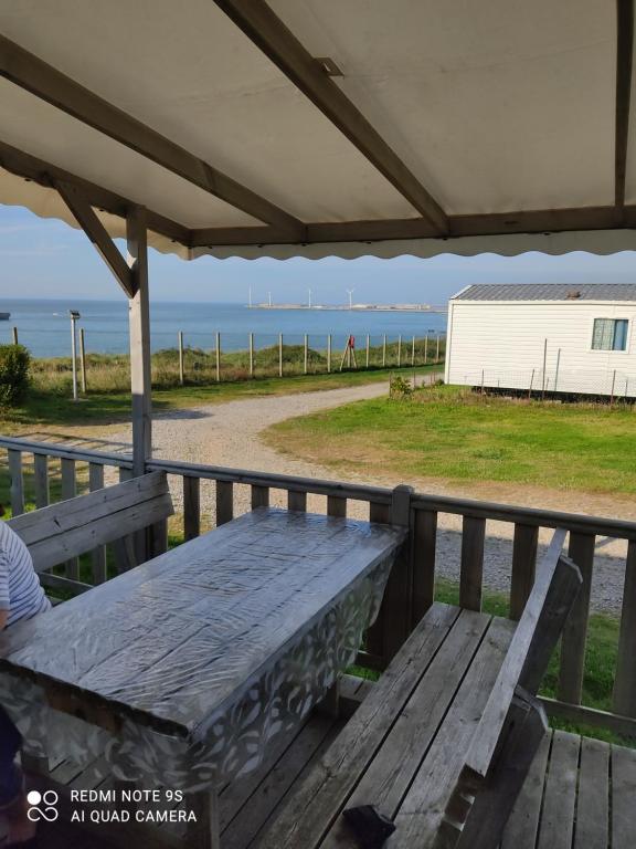 uma mesa de piquenique num deque com vista para o oceano em Camping du phare d opale p48 em Le Portel