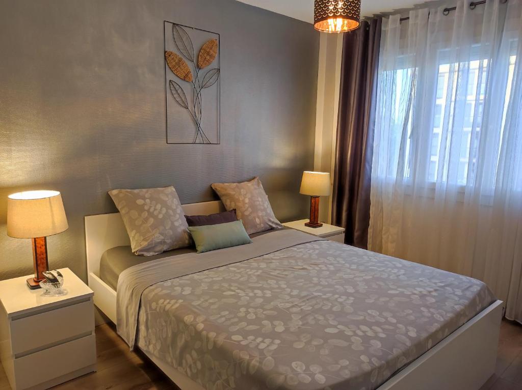a bedroom with a bed with two lamps and a window at Le balcon de la basse centre ville de Perpignan in Perpignan