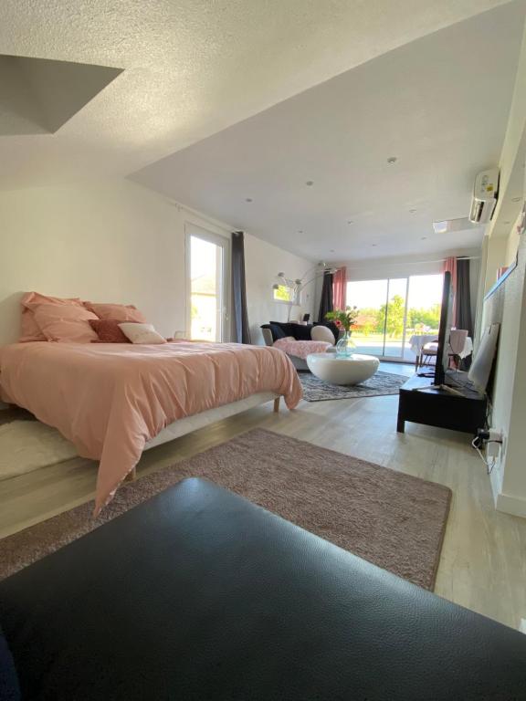 a bedroom with a large bed and a living room at Agréable chambre d’hôte calme avec piscine in Souvans