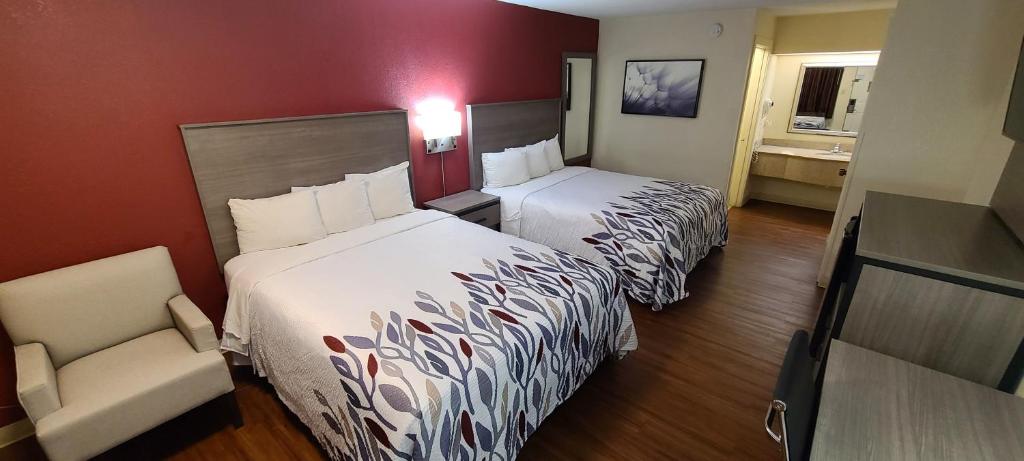 ein Hotelzimmer mit 2 Betten und einem Stuhl in der Unterkunft Red Roof Inn & Suites Cornelius - Lake Norman in Cornelius