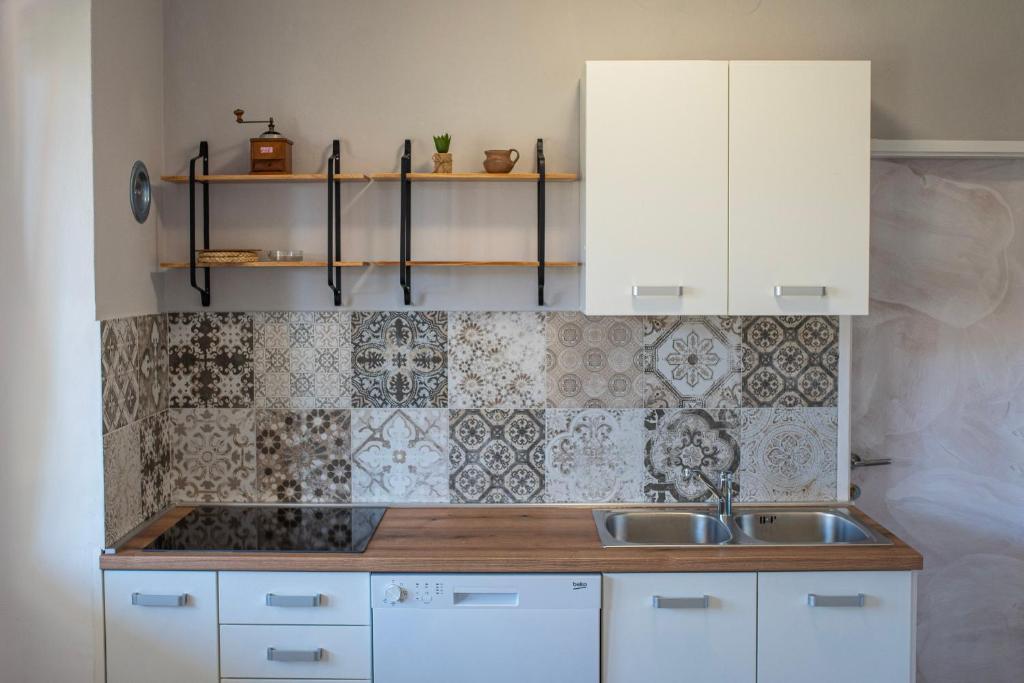 kuchnia z białymi szafkami i zlewem w obiekcie Apartmani Nana Mija w mieście Pag