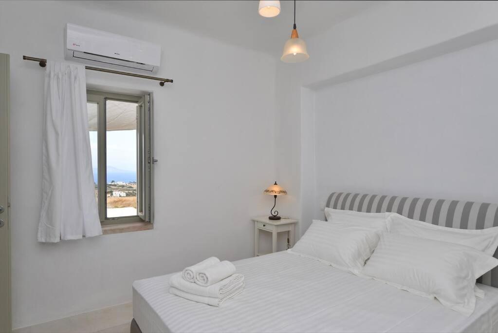 biała sypialnia z łóżkiem i lustrem w obiekcie White House with Sea View w mieście Ambelas
