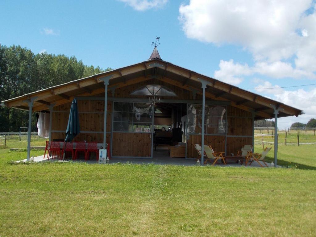 a large building with a table and chairs in a field at Camping du Petit Gué du Roi in Cléry-Saint-André