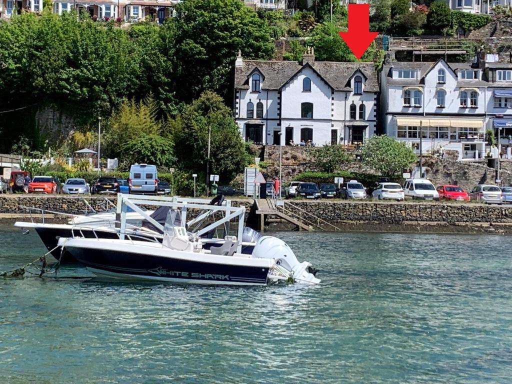 un barco está atracado en el agua junto a las casas en Superb House in Looe, Near Beach and Bars with Great Views and free access to a nearby Indoor Swimming Pool en Looe