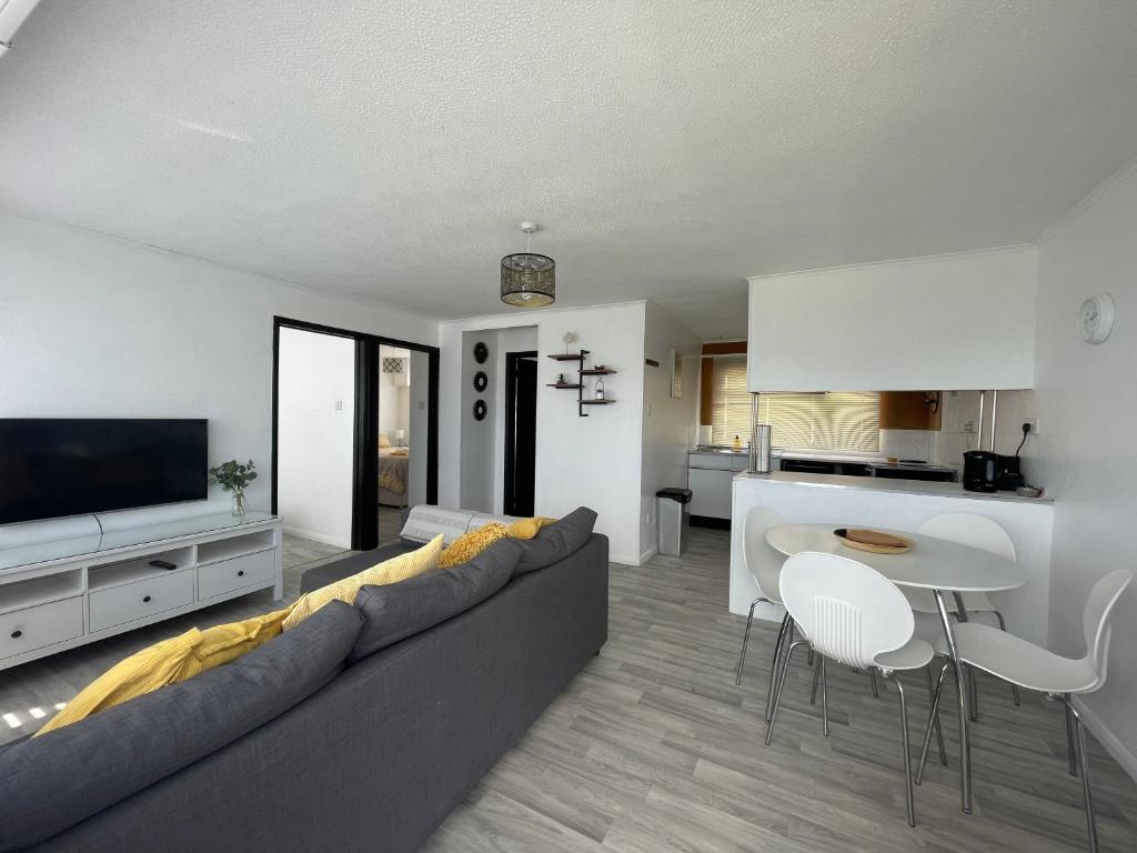 uma sala de estar com um sofá, uma mesa e uma cozinha em Romney Sands Holiday Apartment em New Romney