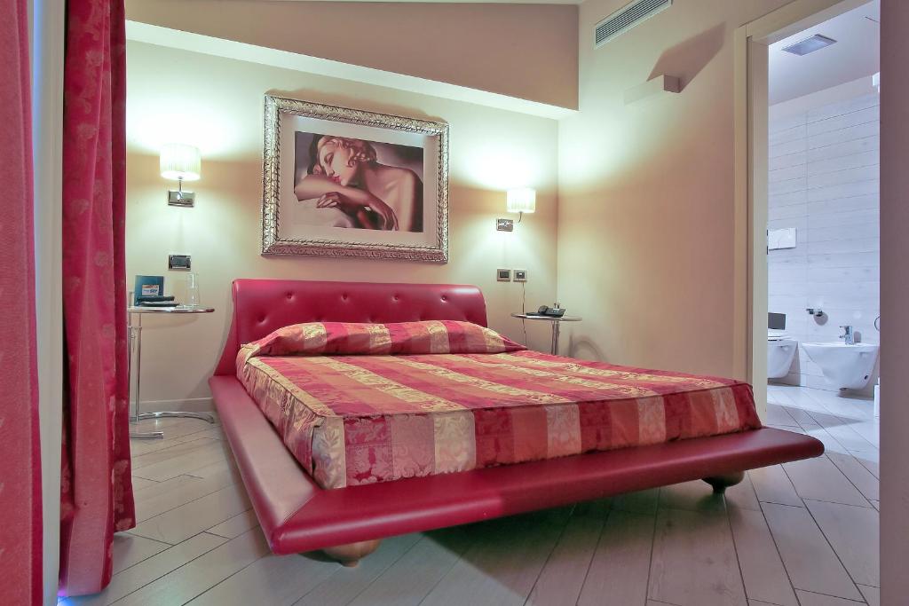 a bedroom with a red bed and a bathroom at Hotel Touring in Fiorano Modenese