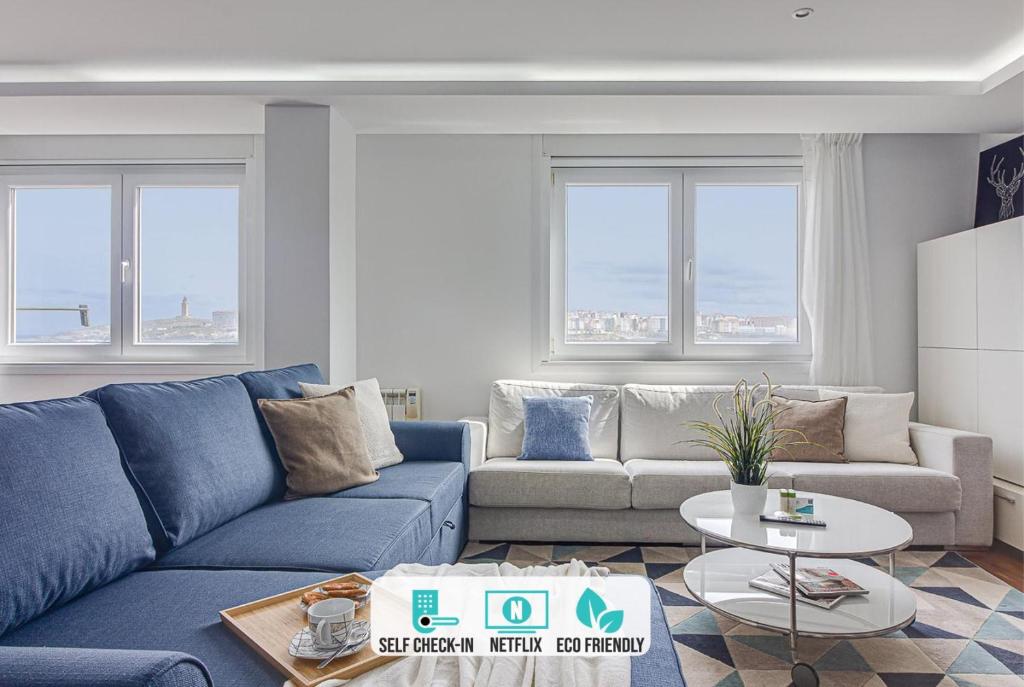 a living room with a blue couch and a table at Riazor Ocean View Apartment in A Coruña