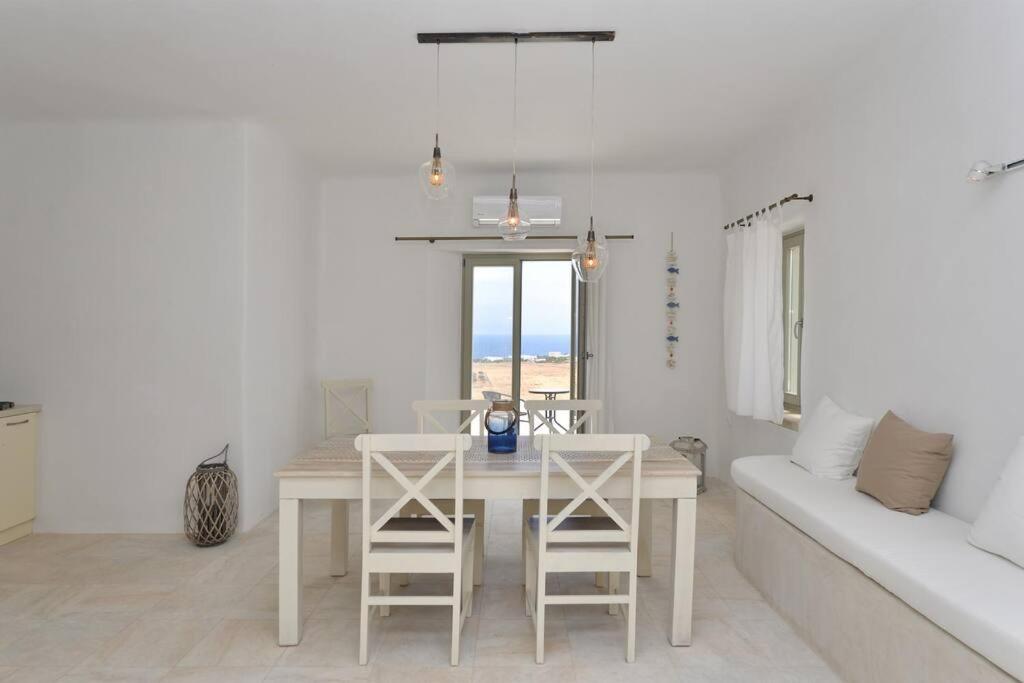 a white dining room with a table and a couch at White house with sea view (number 2) in Ambelas