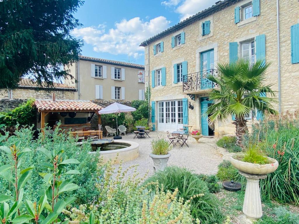 a garden in front of a building with a courtyard at Aux Berges du Libre in Félines-Termenès