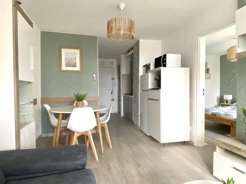 un soggiorno con tavolo e frigorifero bianco di Superbe Apt, 250m plage du môle, clim, parking a Cap d'Agde