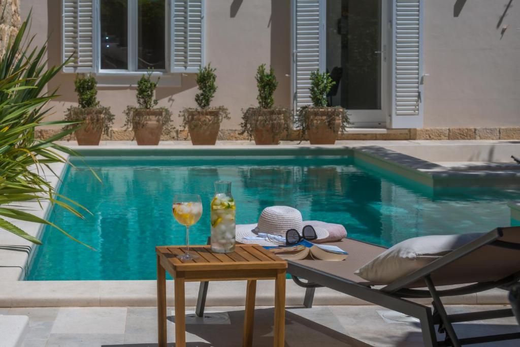 einen Pool mit einem Tisch und einem Glas Wein in der Unterkunft Villa Flores Garden in Dubrovnik