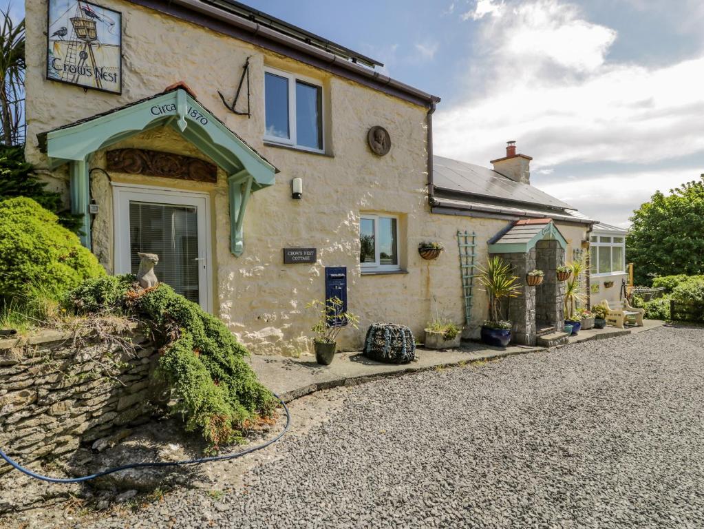 a stone house with a driveway in front of it at Crow's Nest Cottage in Llanallgo