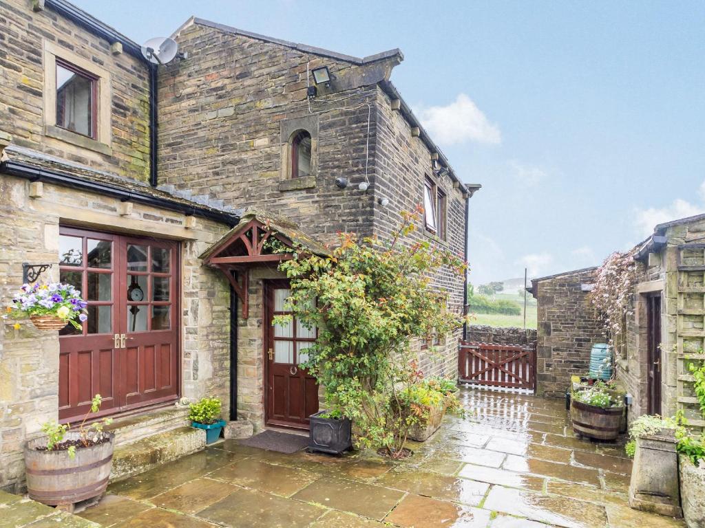 een oud stenen huis met een houten deur bij Green Clough Farm in Bradford