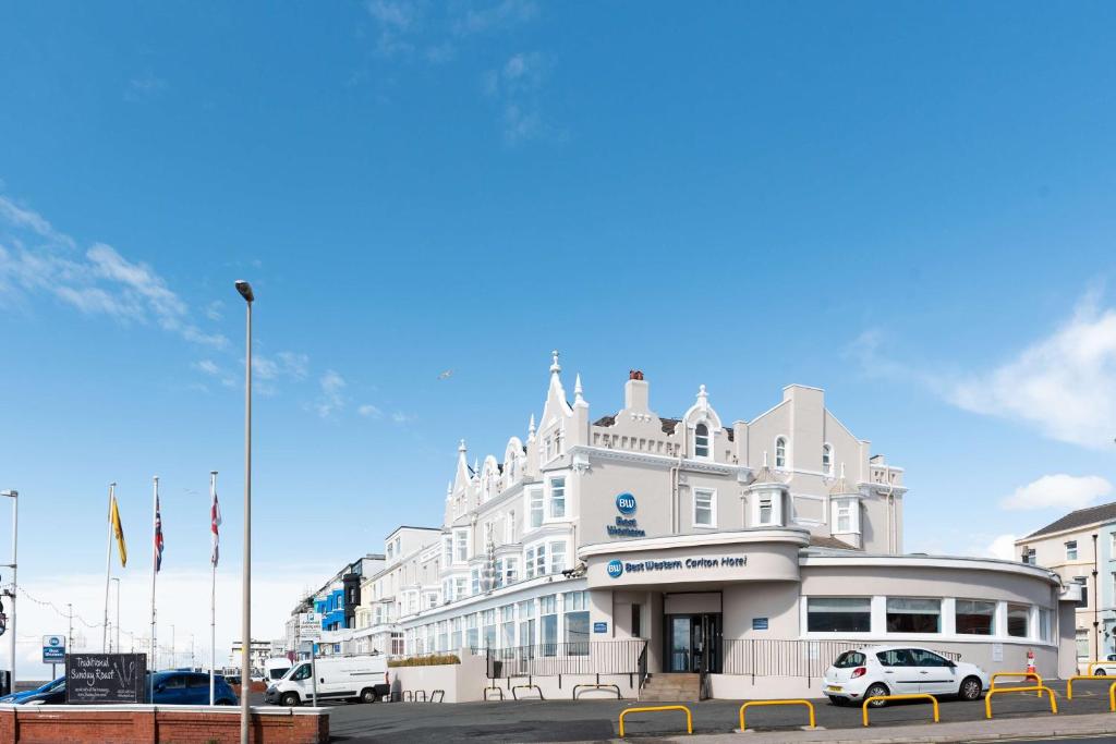um edifício branco com carros estacionados em frente em Best Western Carlton Hotel em Blackpool
