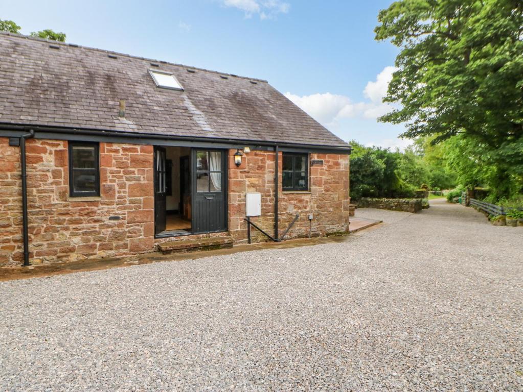 een oud stenen huis met een grindoprit bij The Old Byre in Sandford