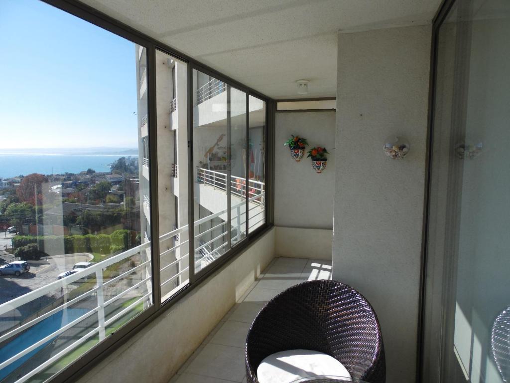 a balcony with a chair and a large window at Laura Barros, Con Con in Concón