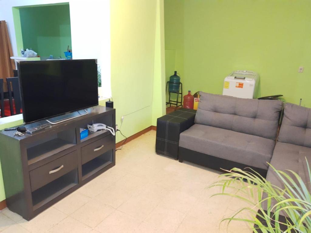 sala de estar con sofá y TV de pantalla plana en CASA CERCA DE LA PLAYA en Puerto Escondido