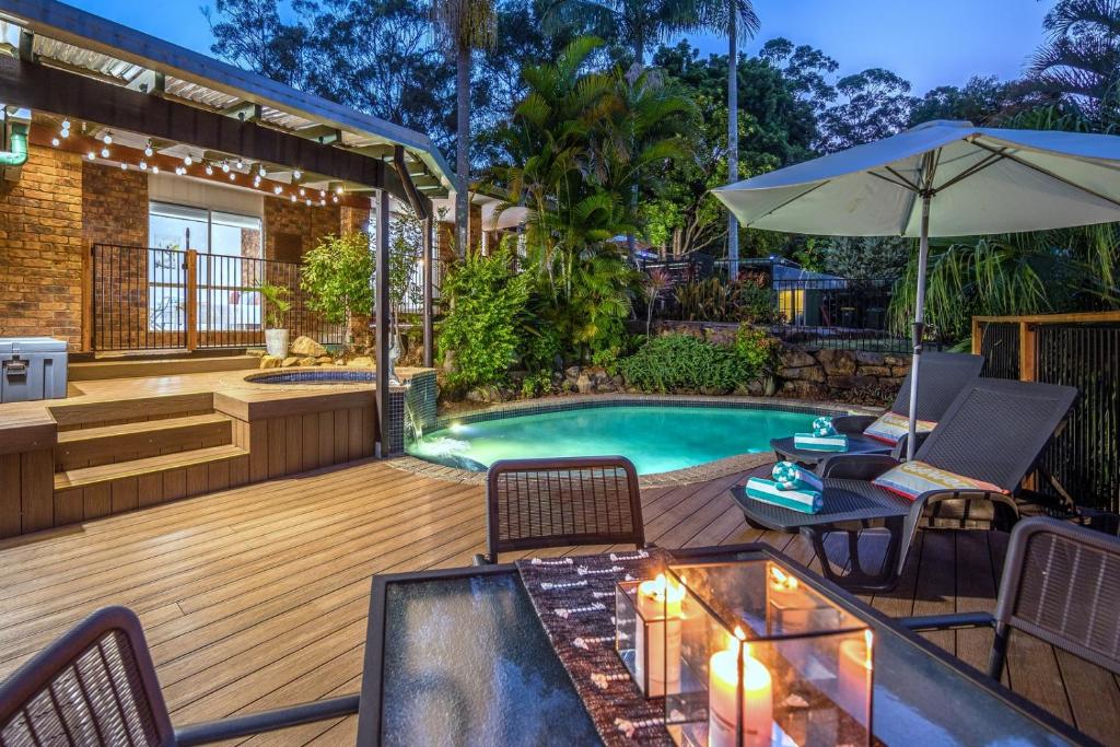 an outdoor deck with a pool and a table and chairs at The Hillside Retreat in Mount Tamborine