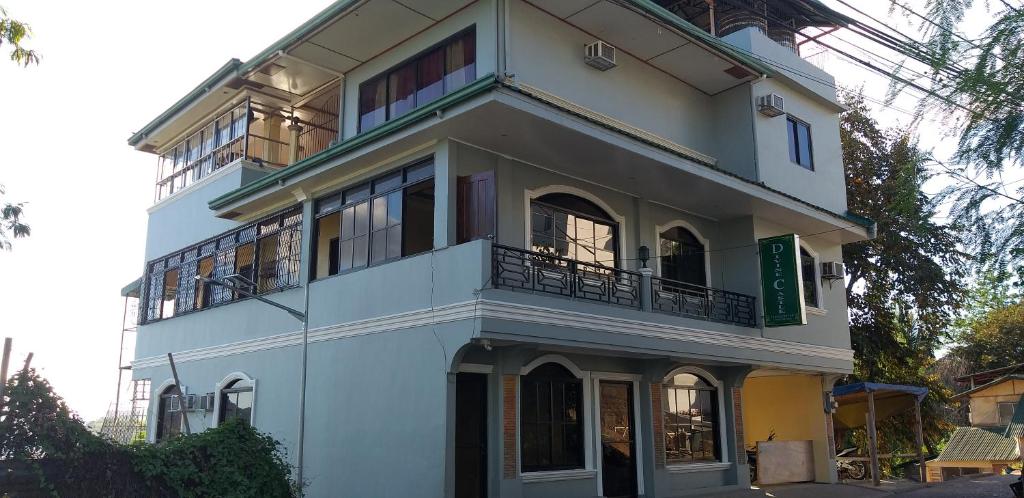 a white building with a balcony on the side of it at Divine Castle Travelers Inn in Coron