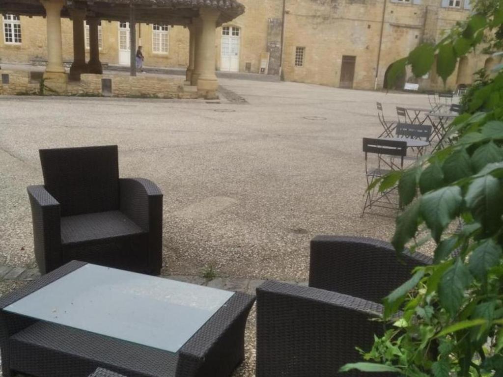 - un groupe de chaises et une table dans une cour dans l'établissement Maison confortable avec balcon au cœur de Cadouin, proche de Dordogne et grands sites touristiques - FR-1-616-196, au Buisson de Cadouin