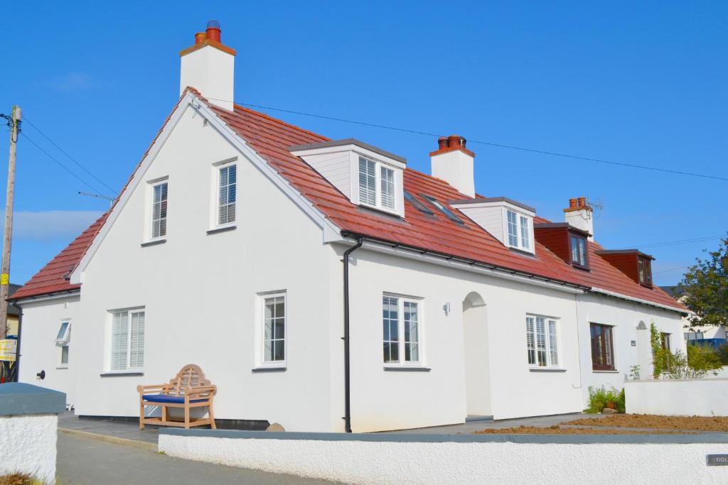 a white house with a red roof at One Dolfor in Pwllheli